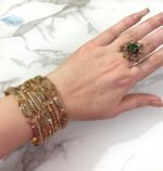 A hand adorned with a beautiful set of antique gold bangles featuring intricate floral and paisley motifs, perfect for traditional and bridal wear.