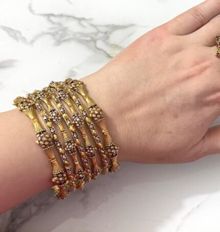 Elegant gold-plated bangle set with intricate floral detailing, beautifully arranged on a woman's wrist for a traditional yet graceful look.