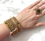 Luxury gold bangles with red crystal stones, ideal for bridesmaids or gifting, elegantly worn on a woman’s wrist.