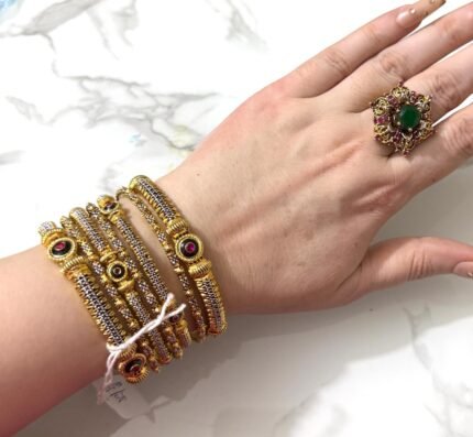 Luxury gold bangles with red crystal stones, ideal for bridesmaids or gifting, elegantly worn on a woman’s wrist.