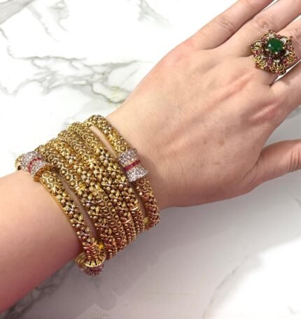 Royal gold-plated bridal bangle set with intricate detailing, displayed elegantly on a decorative surface.