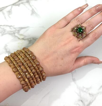 Gold-plated bangle set with polished finish and round ball accents, displayed elegantly on a woman’s wrist.