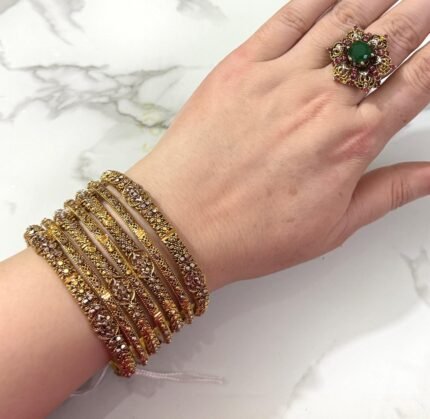 Luxurious traditional gold-plated bangles set with polished finish, beautifully arranged on a soft display background.