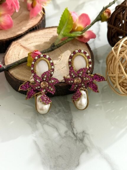 Gold loop earrings adorned with pink crystals, floral motif, and a pearl drop.