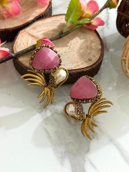 Gold-toned earrings with pink triangular stones, pearl drops, and leaf-inspired golden branch design.