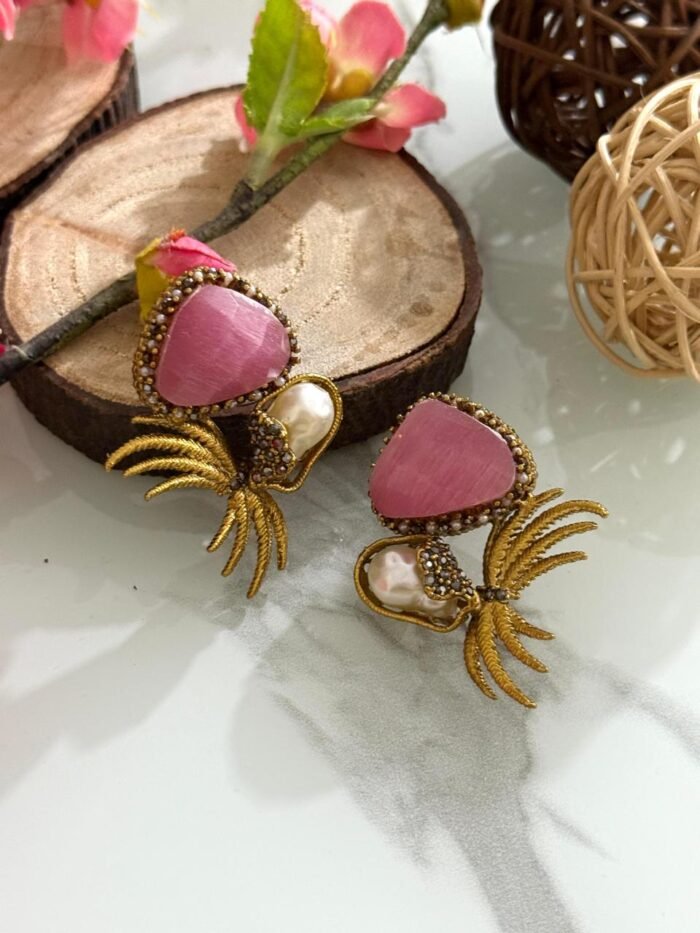 Gold-toned earrings with pink triangular stones, pearl drops, and leaf-inspired golden branch design.