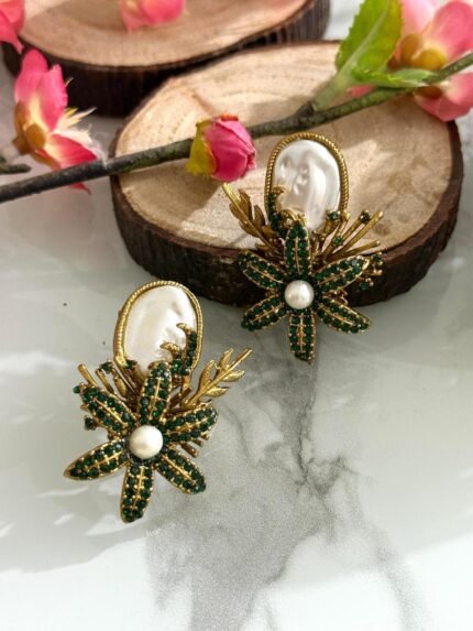 Earrings with green crystal floral design, pearl center, and white oval stone top.