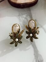 Earrings with green crystal floral design, pearl center, and white oval stone top.