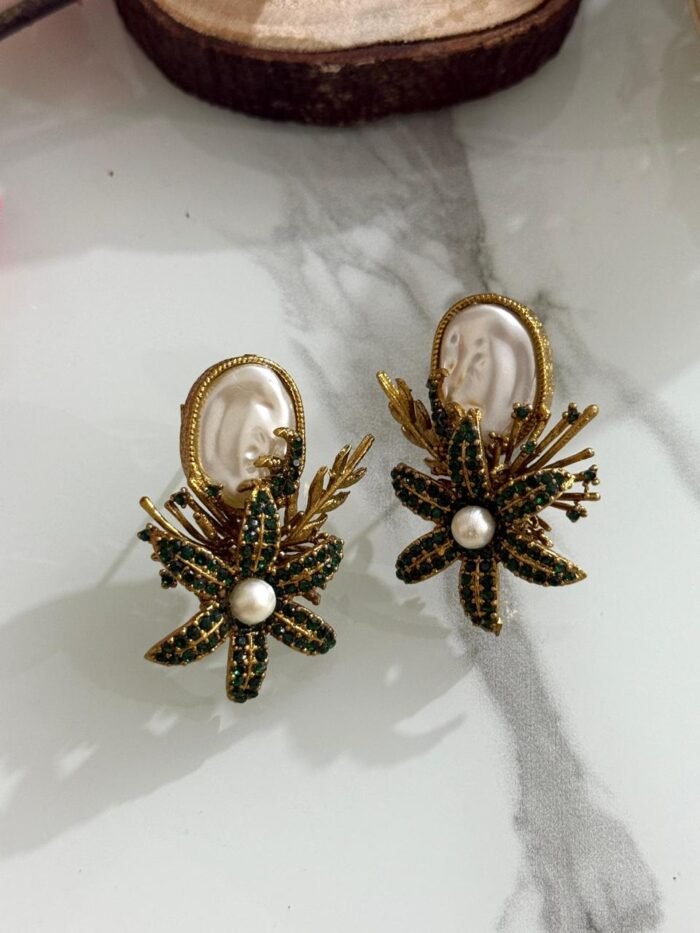 Earrings with green crystal floral design, pearl center, and white oval stone top.