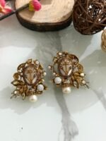 Ornate antique gold earrings with floral and leaf design, white stones, and hanging pearl drop.