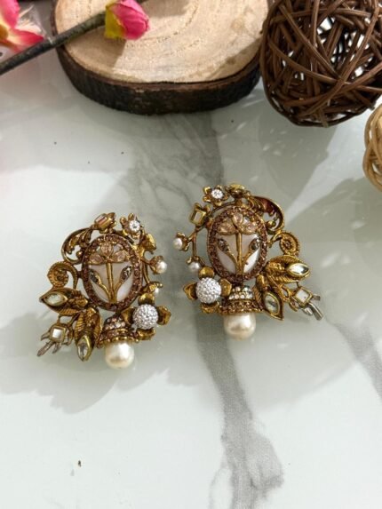 Ornate antique gold earrings with floral and leaf design, white stones, and hanging pearl drop.