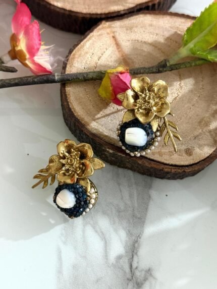 Gold floral stud earrings with navy blue crystal circle and central pearl, accented with a golden leaf.