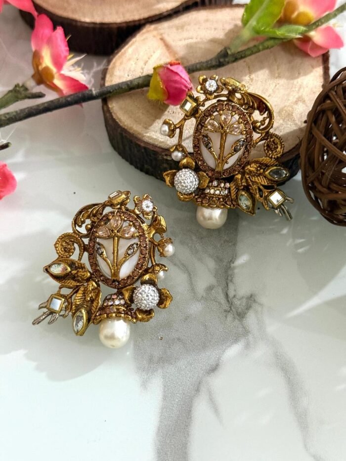 Ornate antique gold earrings with floral and leaf design, white stones, and hanging pearl drop.