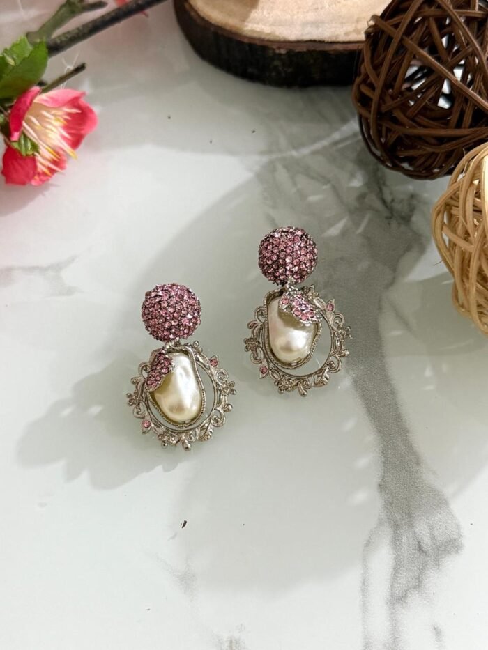 Ornate antique gold earrings with floral and leaf design, white stones, and hanging pearl drop.
