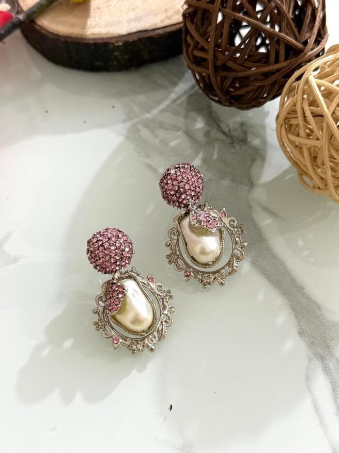 Ornate antique gold earrings with floral and leaf design, white stones, and hanging pearl drop.