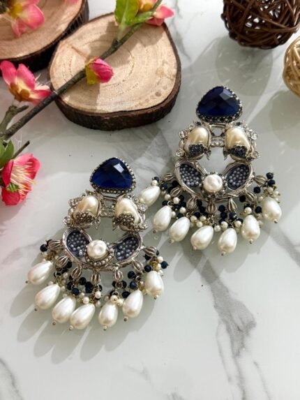 Silver chandbali earrings with navy blue crystal tops, pearl clusters, and intricate silver detailing, adorned with pearl and navy bead drops.