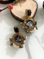 Six ornate earrings with square gemstone studs and circular mosaic centers, decorated with pearl clusters and antique gold detailing, displayed on a marble background.
