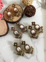 Step into elegance with these Baroque-inspired pearl drop earrings. Featuring a sculpted floral top and ornate golden detailing. Each piece is centered around a lustrous faux pearl with gem-studded accents. Delicate yet bold — perfect for ethnic wear or evening glam. Crafted to capture timeless grace with a garden-fantasy twist.