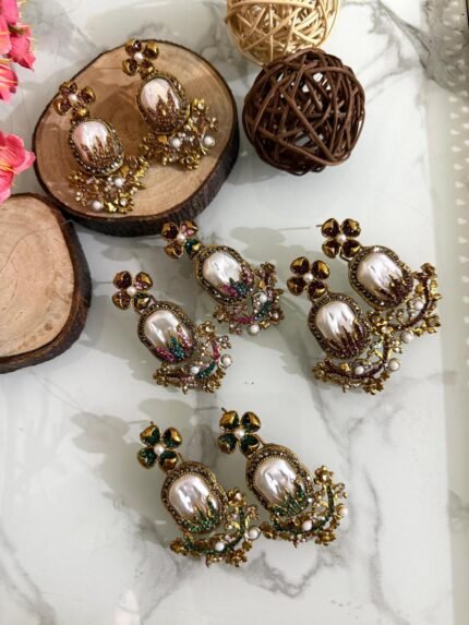 Step into elegance with these Baroque-inspired pearl drop earrings. Featuring a sculpted floral top and ornate golden detailing. Each piece is centered around a lustrous faux pearl with gem-studded accents. Delicate yet bold — perfect for ethnic wear or evening glam. Crafted to capture timeless grace with a garden-fantasy twist.