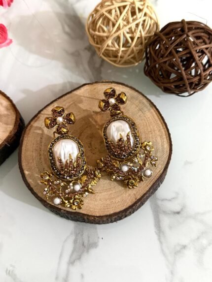 Step into elegance with these Baroque-inspired pearl drop earrings. Featuring a sculpted floral top and ornate golden detailing. Each piece is centered around a lustrous faux pearl with gem-studded accents. Delicate yet bold — perfect for ethnic wear or evening glam. Crafted to capture timeless grace with a garden-fantasy twist.