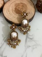 Step into elegance with these Baroque-inspired pearl drop earrings. Featuring a sculpted floral top and ornate golden detailing. Each piece is centered around a lustrous faux pearl with gem-studded accents. Delicate yet bold — perfect for ethnic wear or evening glam. Crafted to capture timeless grace with a garden-fantasy twist.