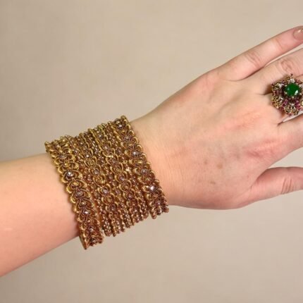 Traditional gold-plated bangles set with intricate detailing, elegantly worn on a woman’s wrist for a festive or cultural occasion