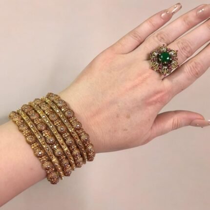 Gold-plated bangle set with polished finish and round ball accents, displayed elegantly on a woman’s wrist.