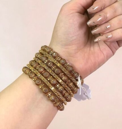 Gold-plated bangle set with polished finish and round ball accents, displayed elegantly on a woman’s wrist.