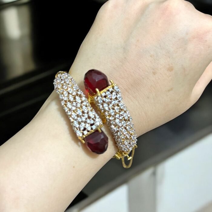 Gold bracelet with red stones and sparkling crystal embellishments.