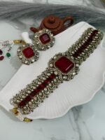 Traditional ruby red stone choker set with matching earrings placed on a white seashell-shaped tray.