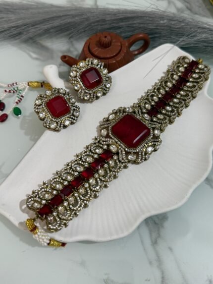 Traditional ruby red stone choker set with matching earrings placed on a white seashell-shaped tray.