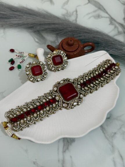 Traditional ruby red stone choker set with matching earrings placed on a white seashell-shaped tray.