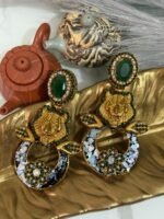 A pair of bold statement earrings with green gemstone studs, gold tiger heads, leaf accents, and circular bases decorated with iridescent shell inlay and floral designs.