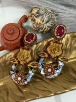 A pair of bold statement earrings with green gemstone studs, gold tiger heads, leaf accents, and circular bases decorated with iridescent shell inlay and floral designs.