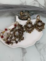 Kundan choker set with red and white beads, large pearl drops, and matching earrings displayed on a shell tray.
