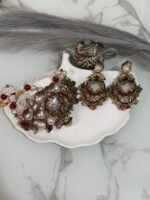 Kundan choker set with red and white beads, large pearl drops, and matching earrings displayed on a shell tray.