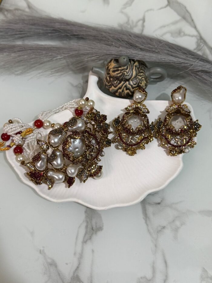Kundan choker set with red and white beads, large pearl drops, and matching earrings displayed on a shell tray.