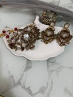 Kundan choker set with red and white beads, large pearl drops, and matching earrings displayed on a shell tray.