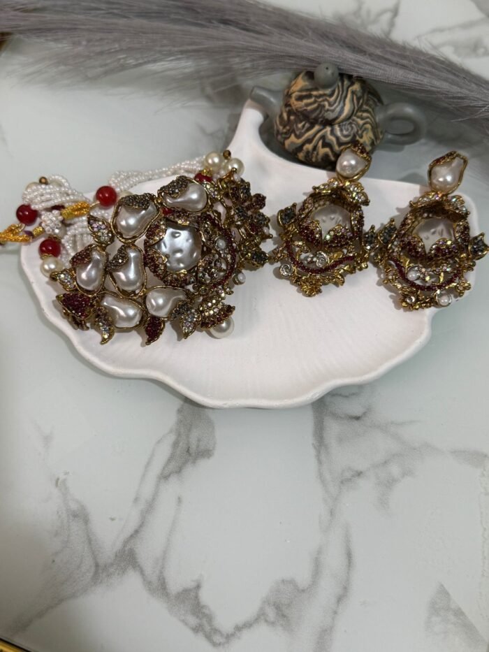 Kundan choker set with red and white beads, large pearl drops, and matching earrings displayed on a shell tray.