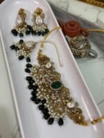 Traditional bridal choker jewelry set with green beads, pearl drops, and matching earrings and maang tikka displayed in a white tray.