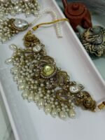 Gold choker jewelry set with yellow center stone, cream pearl drops, and matching earrings and maang tikka displayed in a white tray.