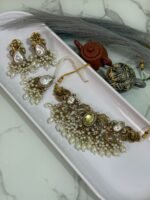 Gold choker jewelry set with yellow center stone, cream pearl drops, and matching earrings and maang tikka displayed in a white tray.
