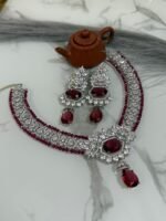 Ruby and diamond necklace set with matching earrings displayed on a marble surface, featuring a rich ruby strand and sparkling diamonds.