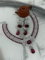 Ruby and diamond necklace set with matching earrings displayed on a marble surface, featuring a rich ruby strand and sparkling diamonds.