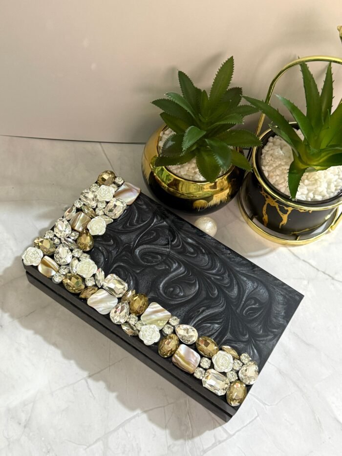 A stylish black clutch with sparkling crystal and mother-of-pearl embellishments, perfect for adding elegance to formal occasions and special events.