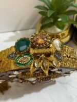 An octagonal clutch with red and gold gemstone embellishments, crystals, pearls, and a gold tassel, placed beside decorative plants.