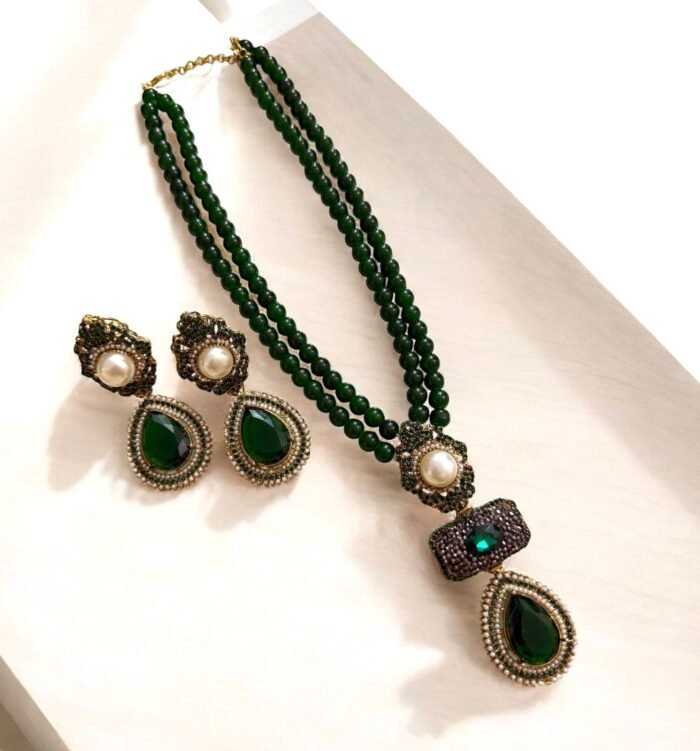 Emerald green necklace and earring set with pearl and crystal accents, displayed on a light-colored background.