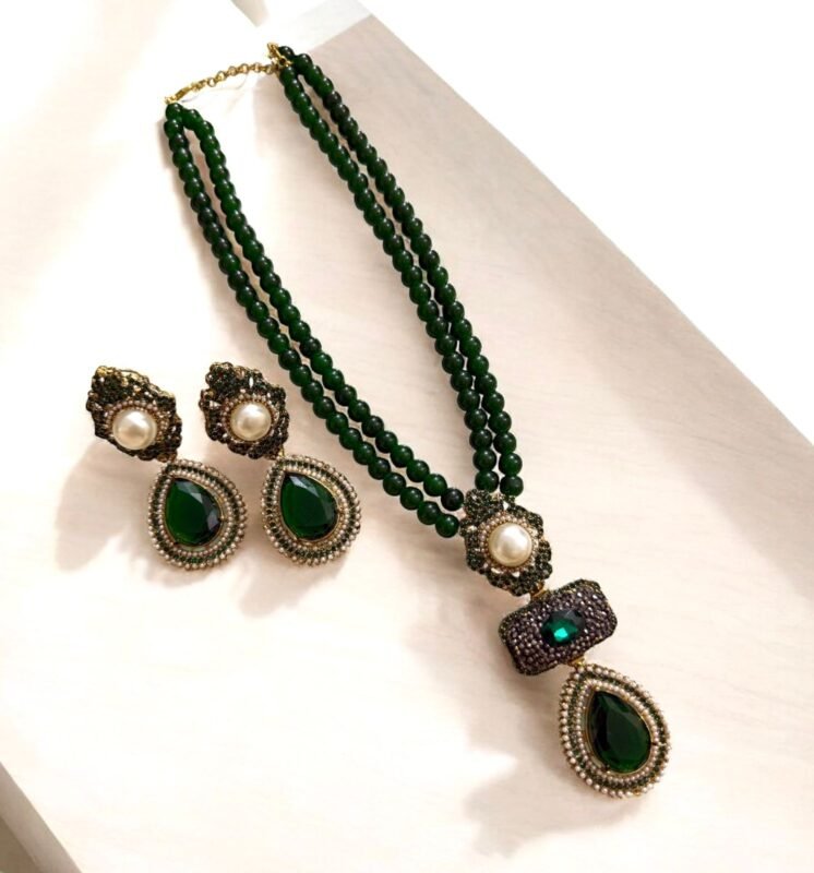 Emerald green necklace and earring set with pearl and crystal accents, displayed on a light-colored background.