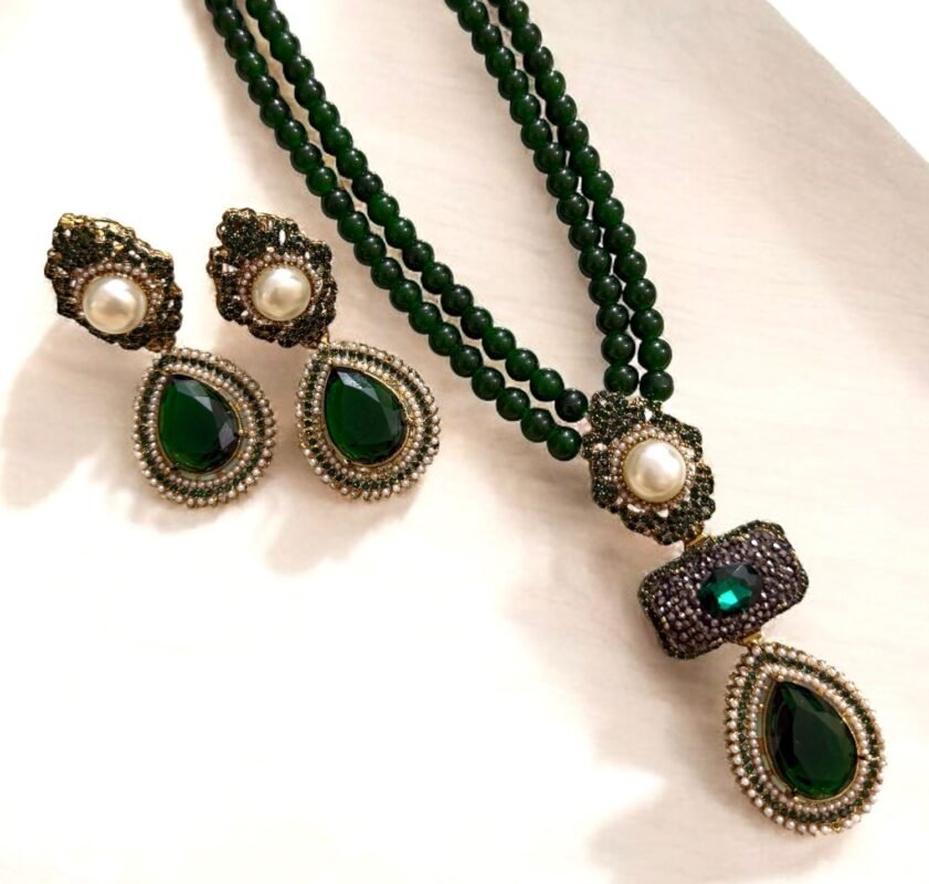 Emerald green necklace and earring set with pearl and crystal accents, displayed on a light-colored background.