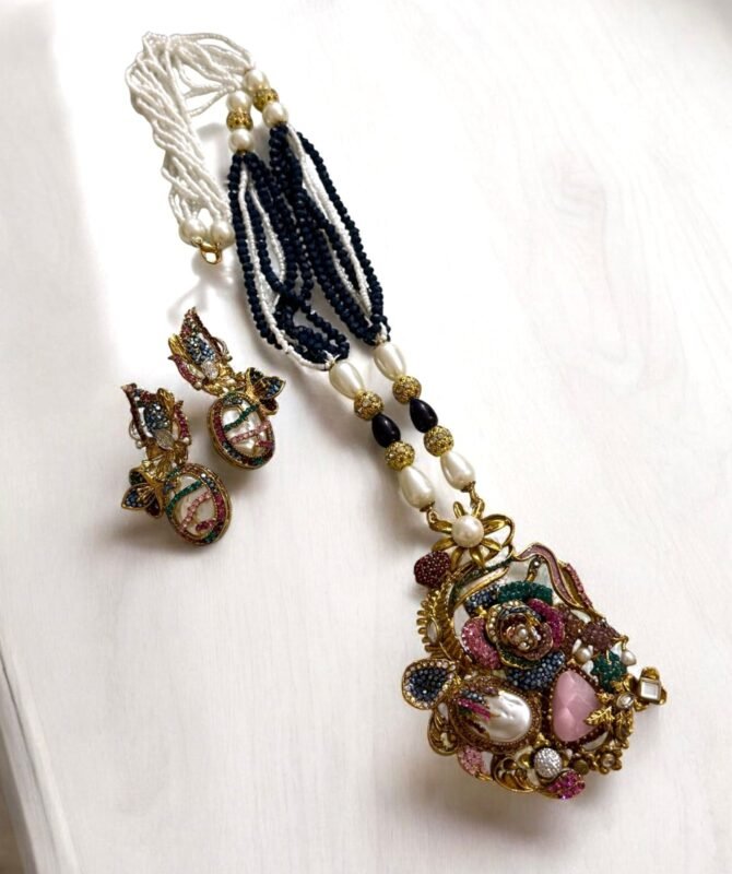 Colorful vintage-style necklace and matching earrings with pearls and crystals, displayed on a light background.
